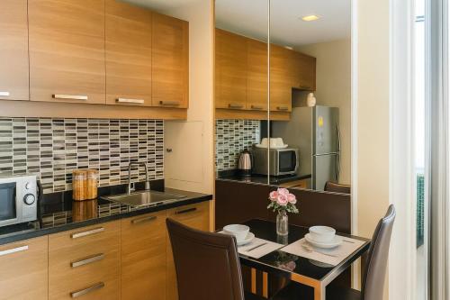 a kitchen with a table with chairs and a microwave at The Wooden Nest Warm Stay at Sukhumvit 8 in Bangkok