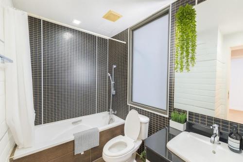 a bathroom with a toilet and a tub and a sink at The Wooden Nest Warm Stay at Sukhumvit 8 in Bangkok