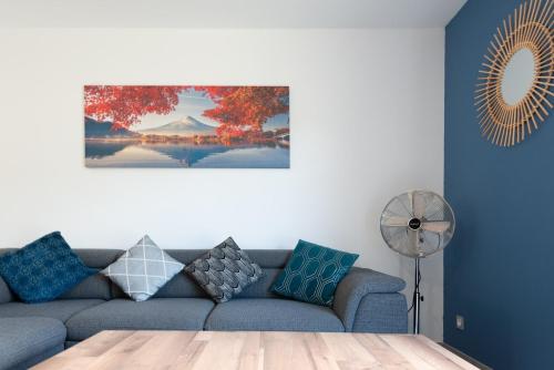 a living room with a blue couch and a fan at Entre genêts et chardons in Banassac