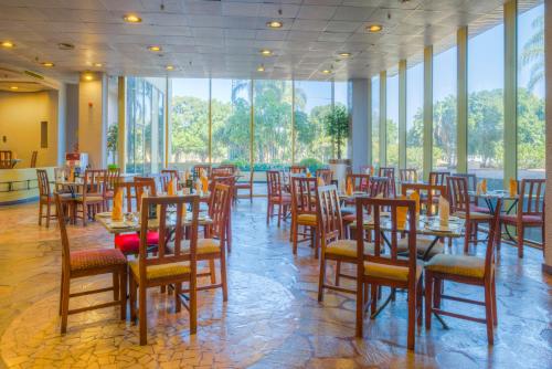 a dining room with tables and chairs and windows at Rainbow Towers Hotel & Conference Centre in Harare