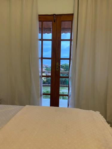a bedroom with a bed and a door with a window at Sol Suítes Caraíva in Porto Seguro