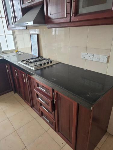 a kitchen with a black counter top and wooden cabinets at Beachfront City Escape Sunset Balcony AC WiFi in Colombo