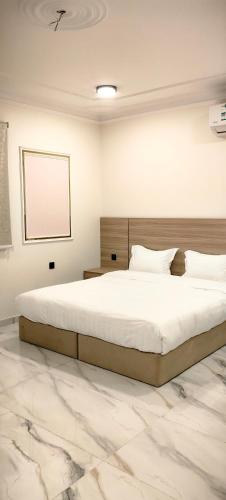 a bedroom with a large white bed with a marble floor at قمة قباءلشقق in Al Madinah