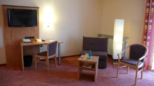 a hotel room with a table and chairs and a television at Hotel Gasthof Käßer in Ansbach