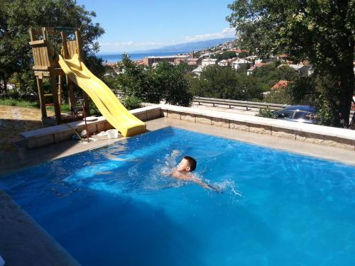 a person swimming in a swimming pool with a slide at BC Bikers Welcome Apartments in Senj