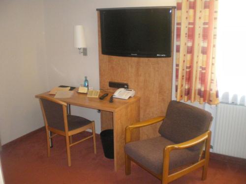 a room with a desk with two chairs and a television at Hotel Gasthof Käßer in Ansbach