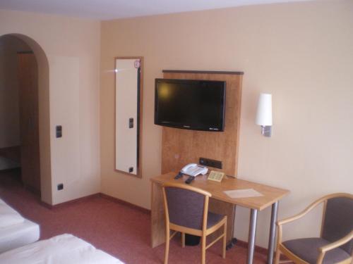 a hotel room with a table and a television on the wall at Hotel Gasthof Käßer in Ansbach
