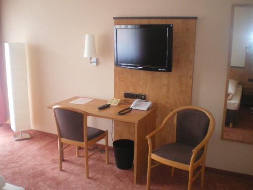 a hotel room with a desk with two chairs and a television at Hotel Gasthof Käßer in Ansbach
