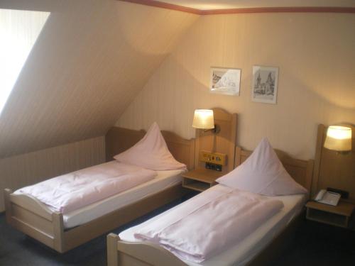 two beds in a small room with two lamps at Hotel Gasthof Käßer in Ansbach