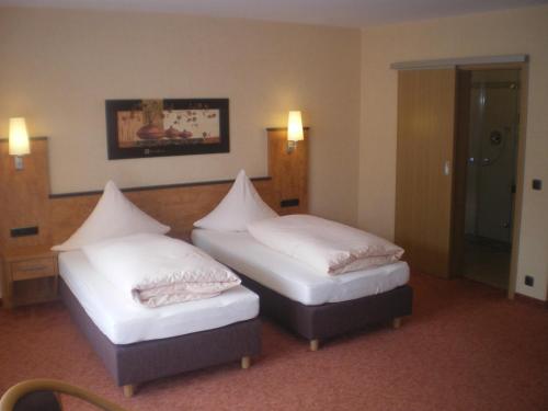 two beds in a hotel room with white sheets at Hotel Gasthof Käßer in Ansbach