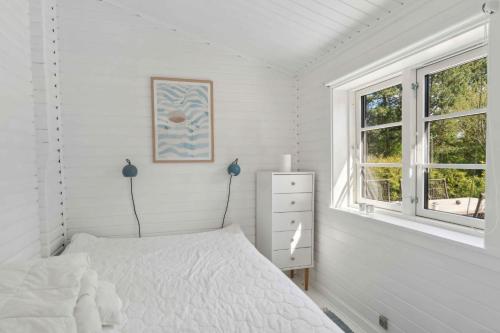 a white bedroom with a bed and a window at Cosy Summerhouse With Private Garden in Nyrup