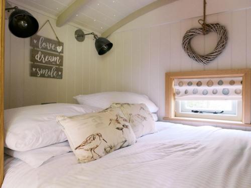 a bedroom with a bed with white sheets and a window at Herbie's Shepherds Hut at Shepherds Lodge Retreat and Wellness in Nottingham