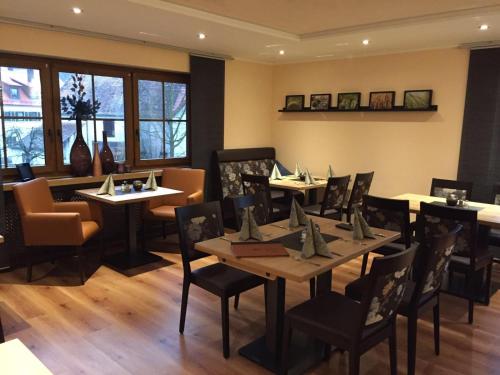 a dining room with tables and chairs and windows at Hotel Gasthof Käßer in Ansbach