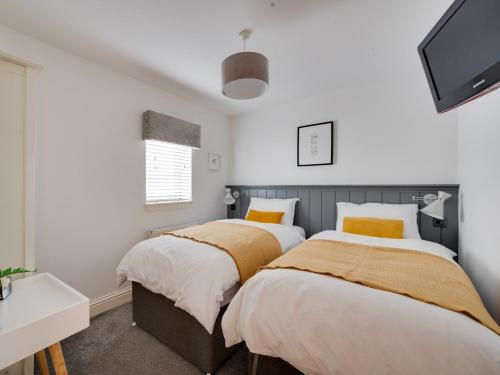 two beds in a bedroom with white walls and yellow pillows at 2 Bed in Anstruther 66733 in Pittenweem