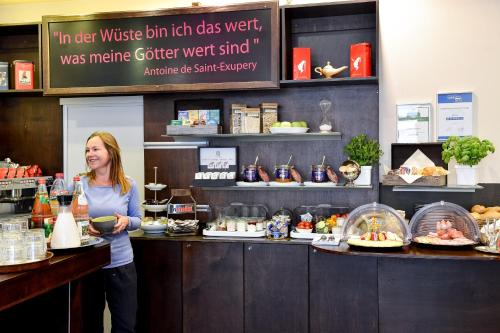 a woman standing behind a counter in a bakery at Hotel Sandmanns am Dom in Cologne
