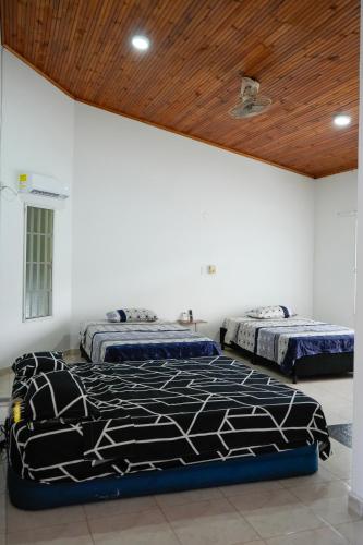 two beds in a room with a wooden ceiling at Casa Hotel Villa Sabrosura in Mariquita