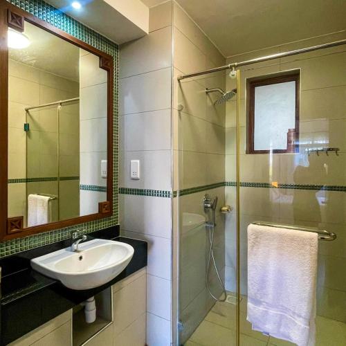 a bathroom with a sink and a shower with a mirror at Zuri's Beachfront Bliss, With Beach Access -Sultan Palace in Mtwapa