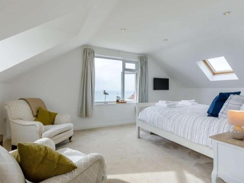 a white bedroom with a bed and a window at 4 Bed in West Bay 86538 in Bridport