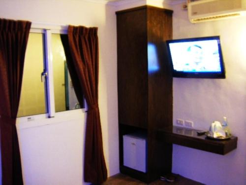 Zimmer mit einem TV an einer Wand mit einem Vorhang in der Unterkunft Baseball Hotel in Hsinchu