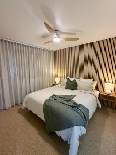 a bedroom with a bed with a ceiling fan at Fletcher Christian Apartments - Manava Suites in Burnt Pine