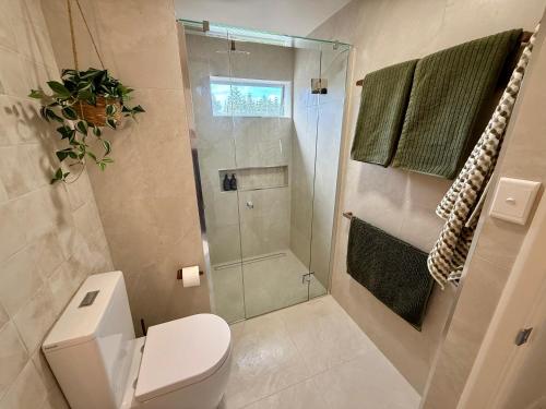 a bathroom with a toilet and a glass shower at Fletcher Christian Apartments - Manava Suites in Burnt Pine