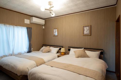 two beds sitting in a room with a window at Kamifurano House in Kami-furano