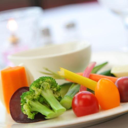 a plate with broccoli tomatoes and other vegetables on it at 箱根エレガンス in Hakone