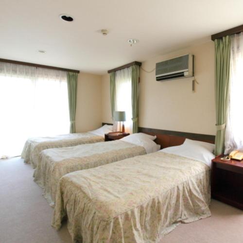 a hotel room with three beds and a window at 箱根エレガンス in Hakone