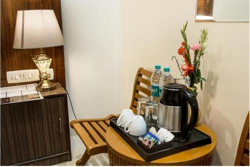 a table with a tea kettle and a vase of flowers at Hotel Luck Recdancy mahipalpur in New Delhi