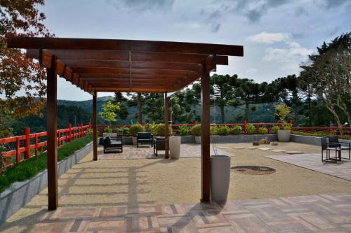 a wooden pavilion with chairs and tables in a park at Matsubara Pousada in Campos do Jordão