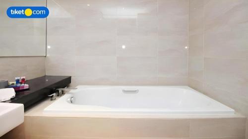 a white bath tub in a bathroom at Hotel Dafam Pacific Caesar in Surabaya