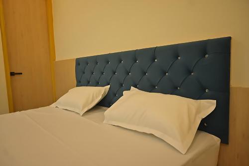 a bed with a blue headboard and white pillows at Shree shyam hotel & restaurant in Mahendragarh