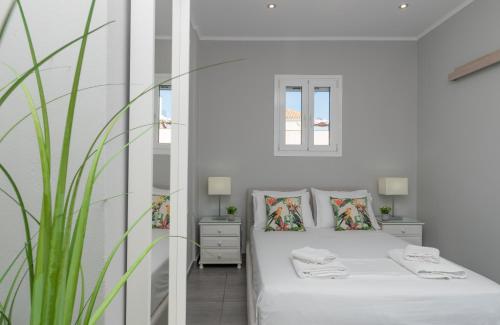 a white bedroom with a bed and a mirror at Demargia Villa C - Loft Apartment in Zakynthos Town in Zakynthos Town