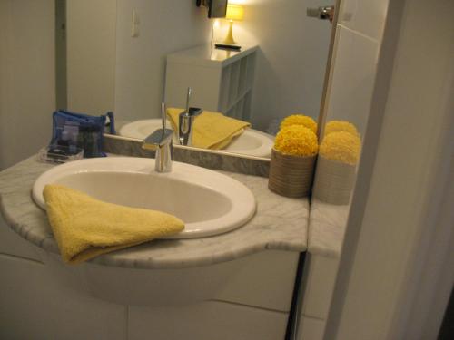 a bathroom sink with a yellow towel and a mirror at Studio du Lac in Cannes