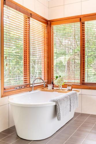 a bath tub in a bathroom with windows at Beautiful 2BR Tranquil Rainforest Retreat Escape Free Wifi in Springbrook