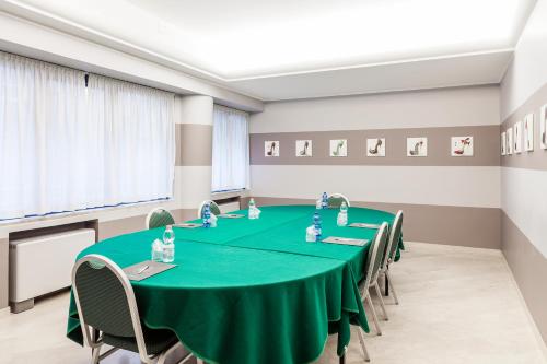 a conference room with a green table and chairs at Hotel Des Etrangers in Milan