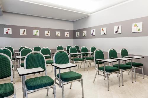 a room with green chairs and tables and pictures on the wall at Hotel Des Etrangers in Milan