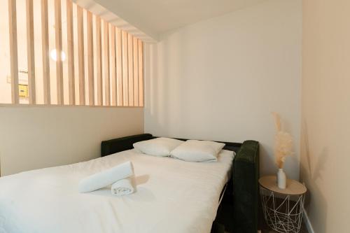 a bedroom with a bed with white sheets and a window at Le Velours in Valence