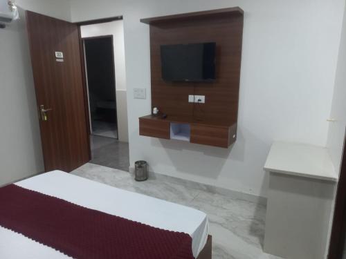 Un dormitorio con una cama y un televisor de pantalla plana. en hotel Sachin INN, en Etāwah