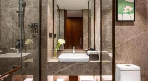 a bathroom with a sink and a shower and a toilet at Ramada Encore by Wyndham Wuhan Caidian in Wuhan