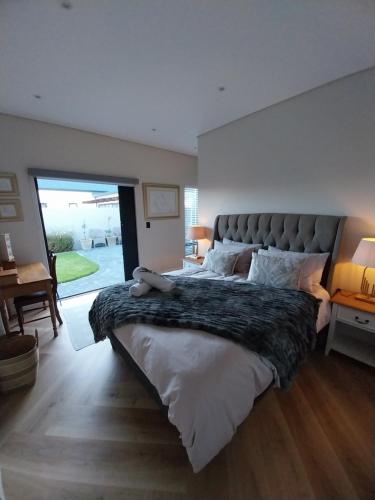 a bedroom with a large bed with a teddy bear on it at White Feather Wellness Room and Beauty Spa in Yzerfontein