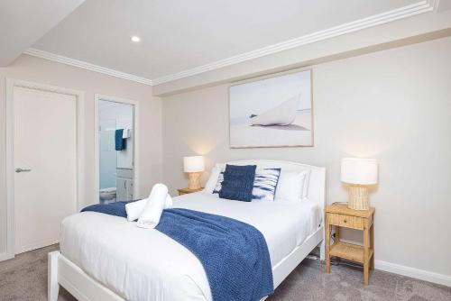 a white bedroom with a bed and two lamps at On the Beach Getaway in One Mile