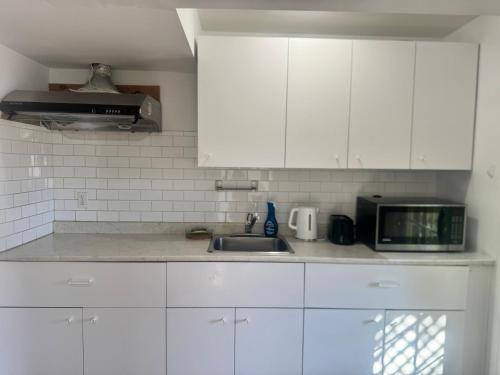 una cucina con mobili bianchi, un lavello e un microonde di Cozy home a Calgary