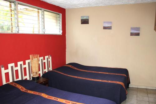 1 dormitorio con 2 camas y pared roja en Ximenas Guest House en San Salvador