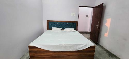 a bedroom with a bed with white sheets and a wooden floor at HOTEL O BLUE ROSE in Sītāpur