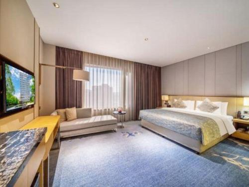 een slaapkamer met een groot bed en een bank bij Wojo Hotel in Tashan