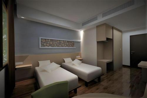 a small room with two beds and a chair at Ayola First Point Hotel Pekanbaru in Sultan Syarif Kasim II International Airport