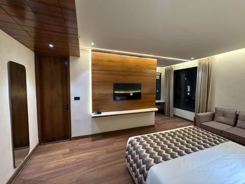 a hotel room with a bed and a flat screen tv at Shanti Sarovar Haridwar in Haridwār