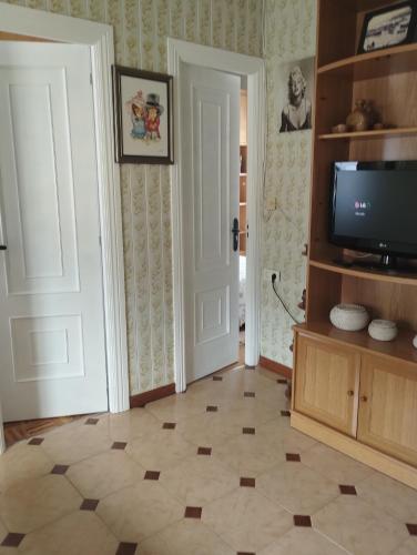 sala de estar con TV y suelo de baldosa. en Casa Belén, en Burela de Cabo