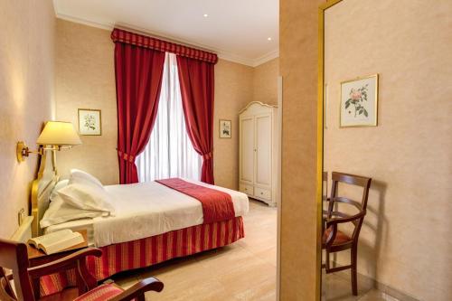 ローマにあるローマン テラスのベッド、デスク、窓が備わるホテルルームです。